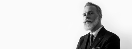 Portrait of bearded handsome gentleman wearing trendy suit over empty white background. Copy Paste text space. Wide. Black and Whiteの写真素材