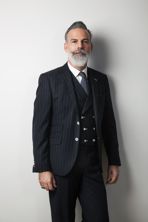 Portrait of confident bearded middle aged gentleman wearing trendy suit over empty white background. Studio shot. Verticalの写真素材