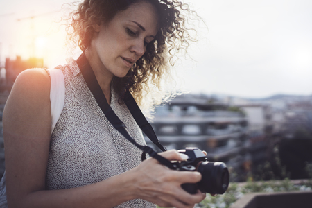 Close up portrait of a smiling pretty girl in casual dress taking photo on a retro camera over...