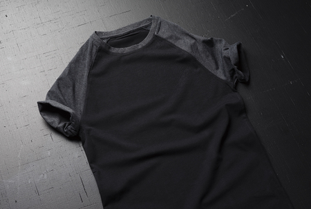 Clean vintage folded t-shirt lies on a black wooden table background. Front view of American Hipsters retro classic clothes.の写真素材