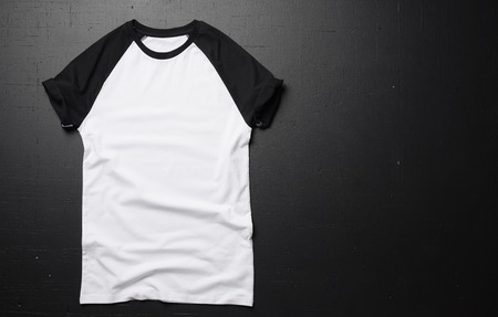 Clean vintage t-shirt lies on a black wooden table background. Front view of American Hipsters retro classic clothes. Copy paste spaceの写真素材