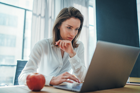 Young entrepreneur female using mobile laptop for looking a new business solution during work process at office.Blurred background.の写真素材