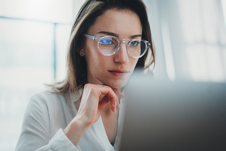 Portrait of pensive confident businesswoman working with laptop computer at modern office.Blurred background.の写真素材