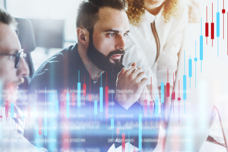 Team of crypro stock traiders sitting front of computer with technical price graph and indicator,...