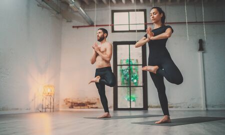 Yoga Practice Exercise Class Concept. Young woman and man practicing yoga indoors. Two sporty people doing exercises.の写真素材