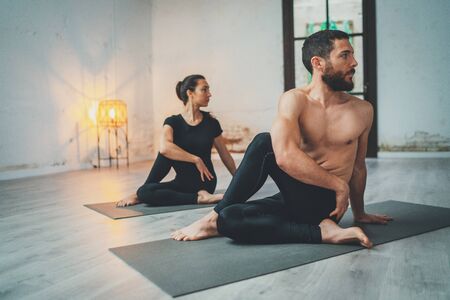 Yoga Practice Exercise Class Concept. Young woman and man practicing yoga indoors. Two sporty people doing exercises.の写真素材
