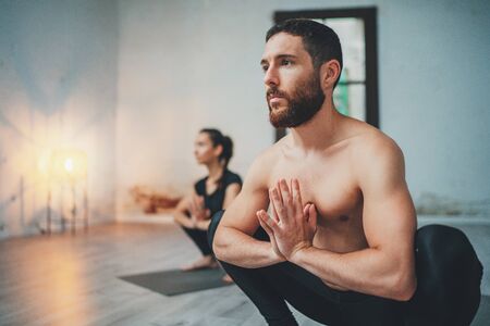 Yoga Practice Exercise Class Concept. Young woman and man practicing yoga indoors. Two sporty people doing exercises.の写真素材