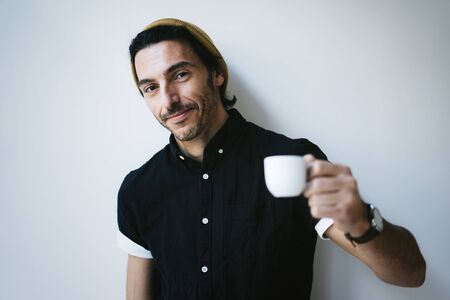 Portrait of an attractive guy with cup of coffeeの写真素材