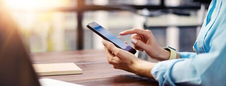 Woman pointing on smartphone screen, chatting in social networks, meeting website, searching internet, sending sms, using text messenger or online banking. Close up of female hands with mobile phoneの写真素材