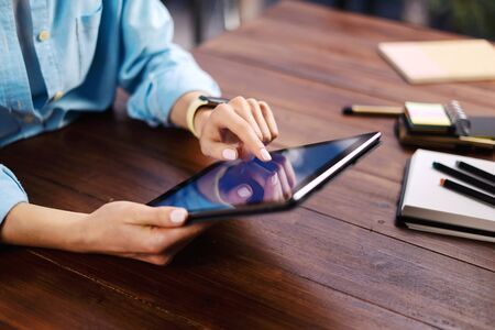 Woman pointing on digital tablet screen, chatting in social networks, meeting website, searching internet, sending sms, using text messenger or online banking. Close up of female hands holding deviceの写真素材