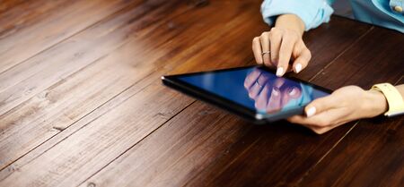 Woman pointing on digital tablet screen, chatting in social networks, meeting website, searching internet, sending sms, using text messenger or online banking. Close up of female hands holding deviceの写真素材