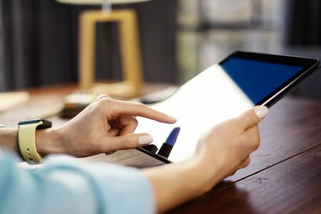 Woman pointing on digital tablet screen, chatting in social networks, meeting website, searching internet, sending sms, using text messenger or online banking. Close up of female hands holding deviceの写真素材