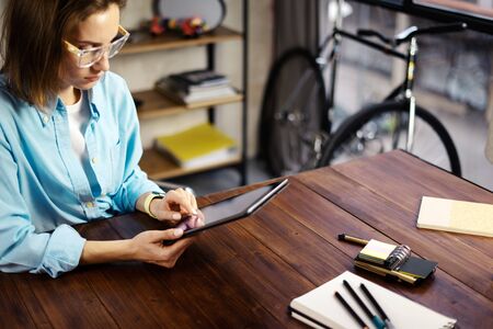 Woman pointing on digital tablet screen, chatting in social networks, meeting website, searching internet, sending sms, using text messenger or online banking. Close up of female hands holding deviceの写真素材