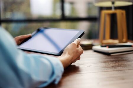 Woman pointing on digital tablet screen, chatting in social networks, meeting website, searching internet, sending sms, using text messenger or online banking. Close up of female hands holding deviceの写真素材