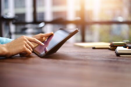 Woman pointing on digital tablet screen, chatting in social networks, meeting website, searching internet, sending sms, using text messenger or online banking. Close up of female hands holding deviceの写真素材