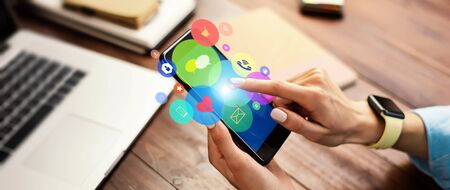 Close-up photo of female hand holding smartphone with media and social networks icons. Concept of digital networkの写真素材