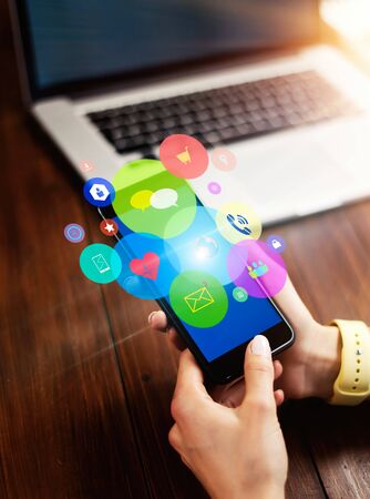 Close-up photo of female hand holding smartphone with media and social networks icons. Concept of digital networkの写真素材