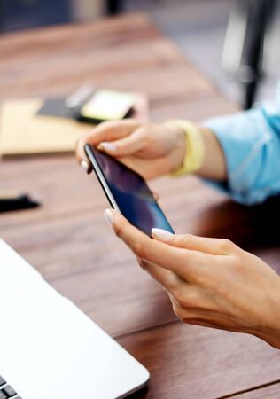 Woman pointing on smartphone screen, chatting in social networks, meeting website, searching internet, sending sms, using text messenger or online banking. Close up of female hands with mobile phoneの写真素材