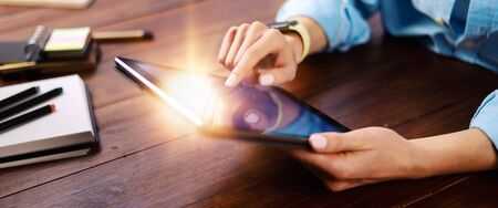 Woman pointing on digital tablet screen, chatting in social networks, meeting website, searching internet, sending sms, using text messenger or online banking. Close up of female hands holding deviceの写真素材