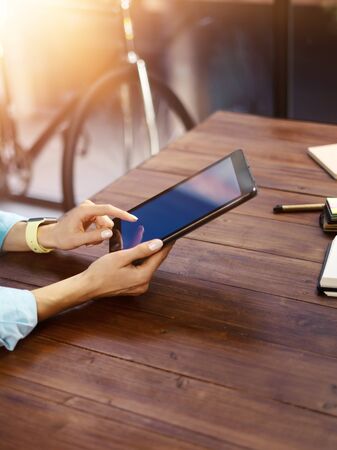 Woman pointing on digital tablet screen, chatting in social networks, meeting website, searching internet, sending sms, using text messenger or online banking. Close up of female hands holding deviceの写真素材