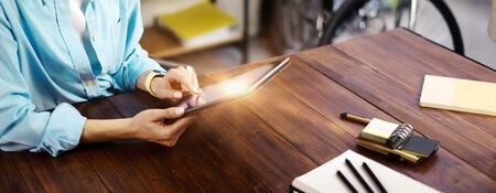 Woman pointing on digital tablet screen, chatting in social networks, meeting website, searching internet, sending sms, using text messenger or online banking. Close up of female hands holding deviceの写真素材