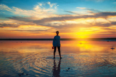 silhouette of a woman on the water at sunset, beautiful sunset sky with clouds, tourism concept.の写真素材