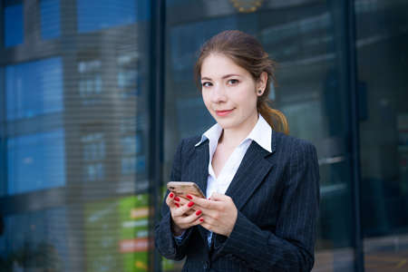a beautiful young brunette girl in a shirt and jacket stands against the background of an office...