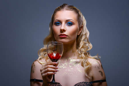 bright make-up on the face of a beautiful woman holding a glass of wine in her hand.の写真素材