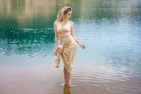 Beautiful slender girl with long hair posing standing in the water.の写真素材