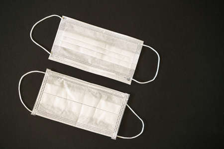 Two white medical masks on a black background.