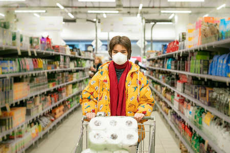 24.03.2020 Russia Saint Petersburg, a young woman in a store in a protective mask selects products.の写真素材
