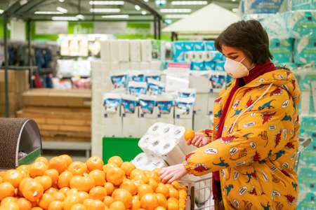 March 24, 2020, Russia Saint Petersburg. A masked woman in a supermarket takes fruit to stock.の写真素材