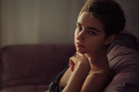 Young cute woman sitting in a chair sad, short hair.の写真素材