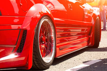 Red sports tuned car rear view of the wheel, close-up . Fashion car day on the roadの写真素材