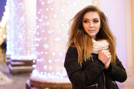 Portrait of a happy young woman on the street with a garland background.の写真素材