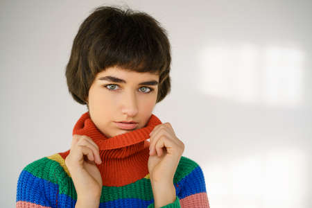 Portrait of a cute girl in a multicolored sweater on a light background.の写真素材