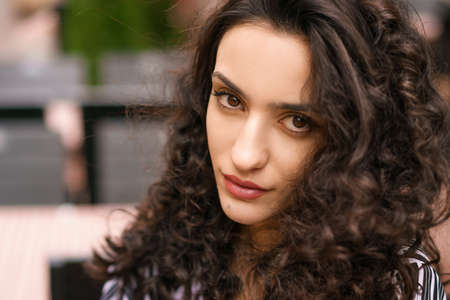 Female portrait close-up, curly hair dark brown eyes, posing on the street . Beautiful brunette womanの写真素材