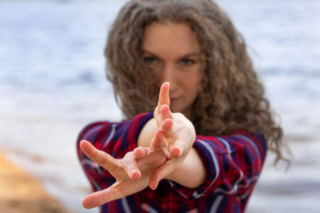 A close-up portrait of a woman dancing on the beach, her hands in front of her in the frame , an...