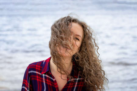 A woman with curly hair walks alone along the riverbank in the wind,の写真素材
