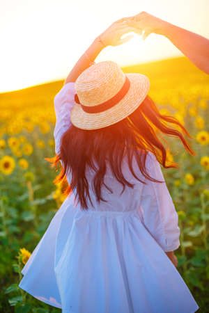 A couple dancing at sunset in a field with blooming sunflowers. Romantic relationships hold each other's handsの写真素材