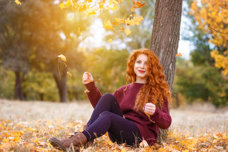 Full length, happy red haired woman in autumn parkの写真素材
