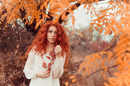 beautiful red-haired young woman in autumn forest