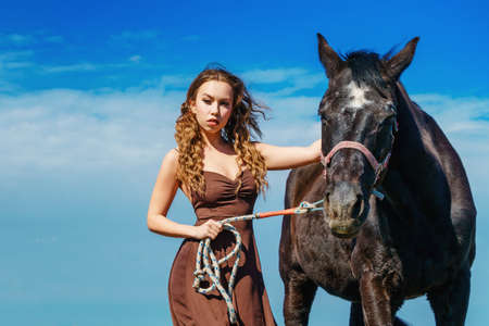 beautiful woman standing in a field with a horse.の写真素材