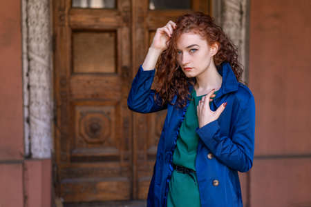 portrait of beautiful woman with red hair in blue cloak posing on camera.の写真素材