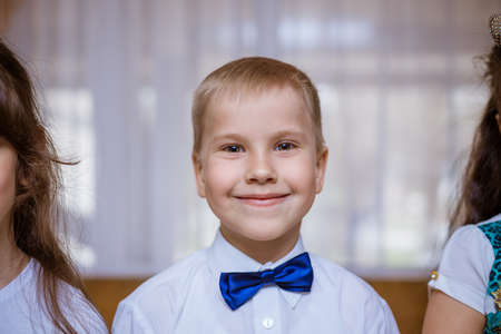 Portrait of a boy in a white shirt and black bow tie, smiling cheerful schoolboyの写真素材