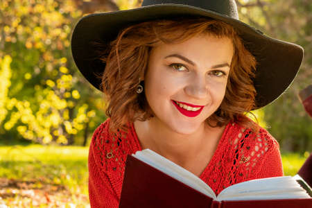 lovely woman reading a book in the autumn Park sitting on the grass