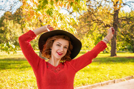 portrait of happy woman in hat hands at the top in autumn Park