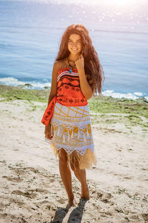 a young beautiful girl with long hair walks on the beach, posing against the sea on a sunny summer...