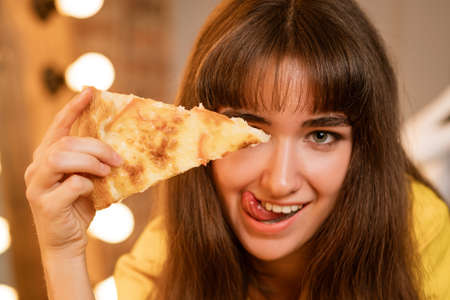 Portrait of a cheerful young woman in close-up with a slice of pizza ,の写真素材