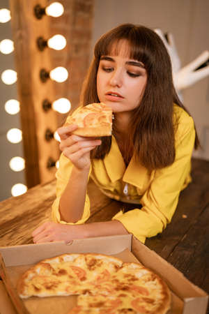 Portrait of a cheerful young woman in close-up with a slice of pizza ,の写真素材